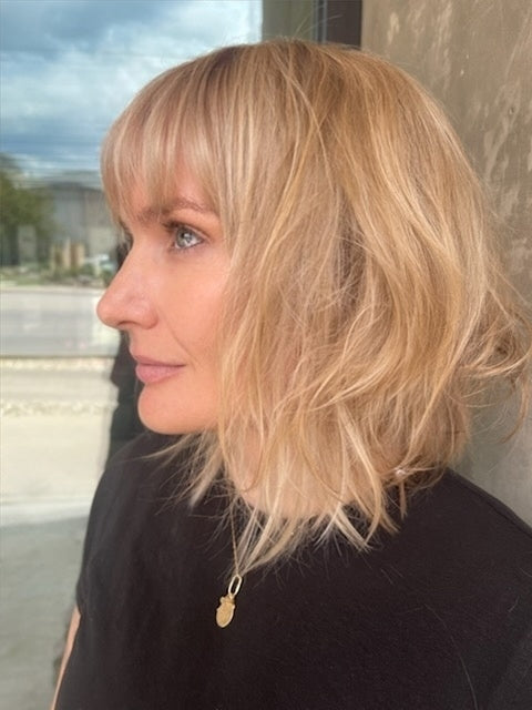 Woman with blonde hair and a black top, standing outdoors.